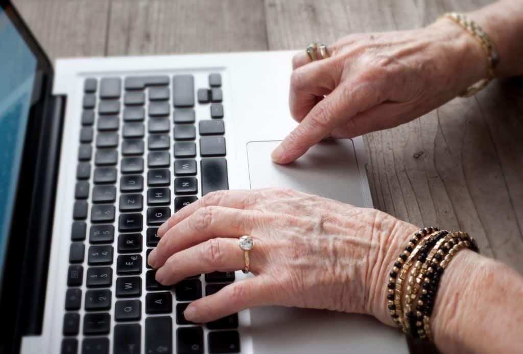 A woman's hand typing on a laptop to find the best computers for seniors in 2023.