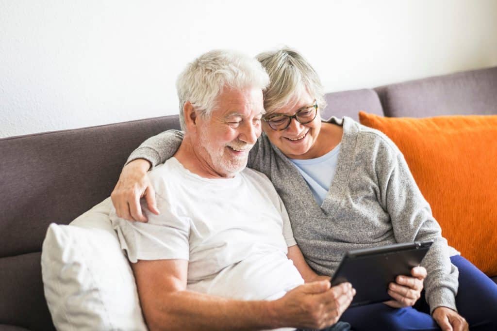 An older couple finding the best tablet for seniors with vision problems while sitting on a couch.