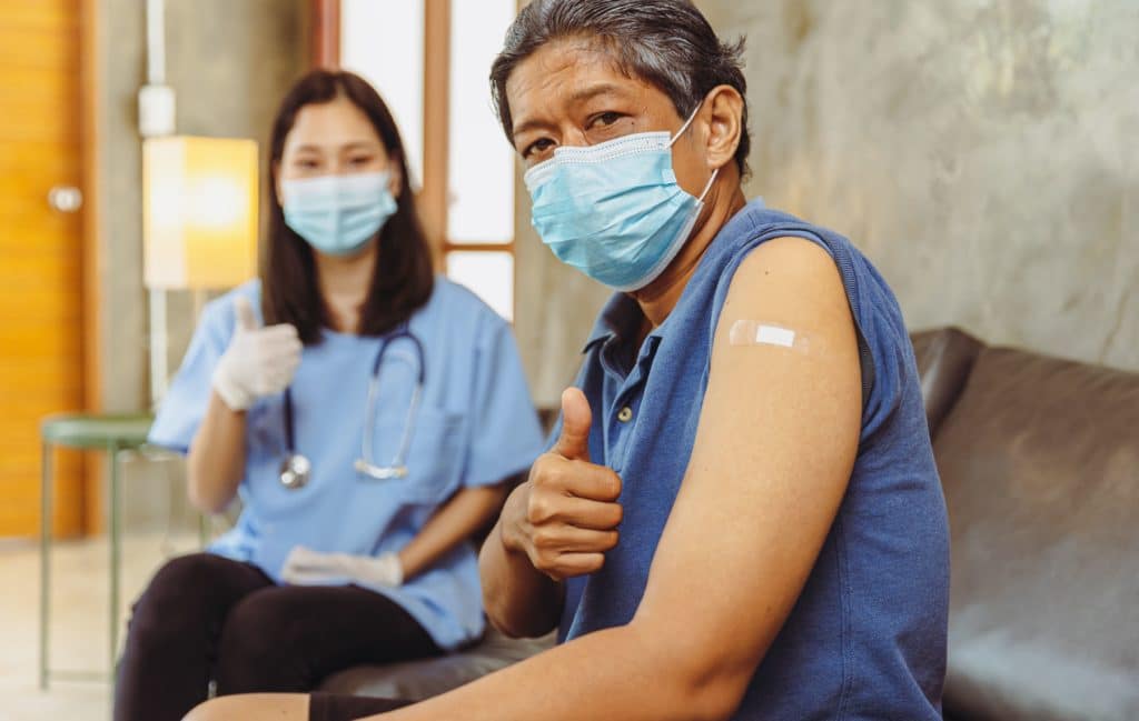 A nurse is giving a thumbs up to a patient while wearing a mask during the free shingles vaccine campaign for seniors in 2023.