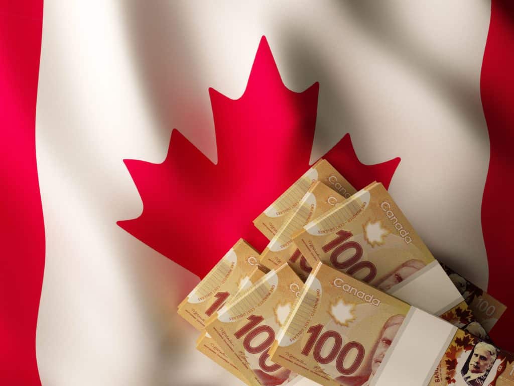 A stack of Canadian dollar bills on a Canadian flag signifies a potential increase in the OAS for seniors over 75 in Canada.