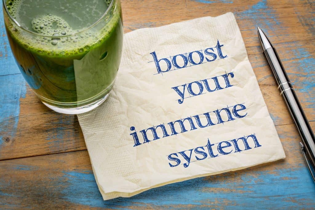 A glass of green juice, the best immune booster for seniors, with a piece of paper saying "boost your immune system.