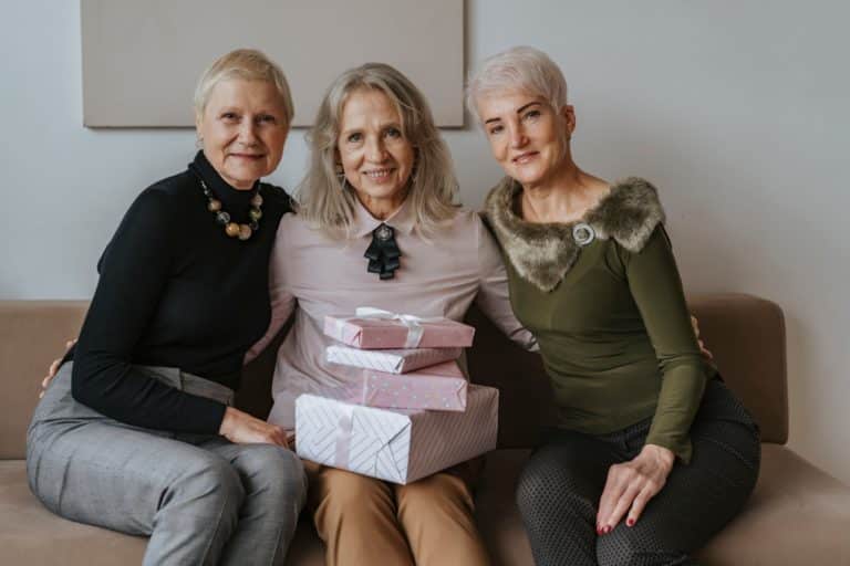 Three charming elderly women on a couch with gift boxes, demonstrating delightful gift options.